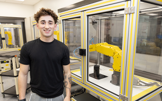 Cole Gerovac in front of robotic arm