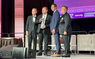 four people pose for photo with award on stage