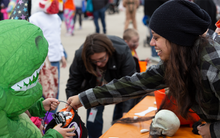 person putting candy in kid's Halloween bucket