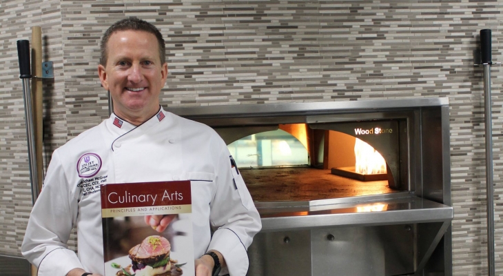 Chef Mike McGreal holding a copy of his textbook, 