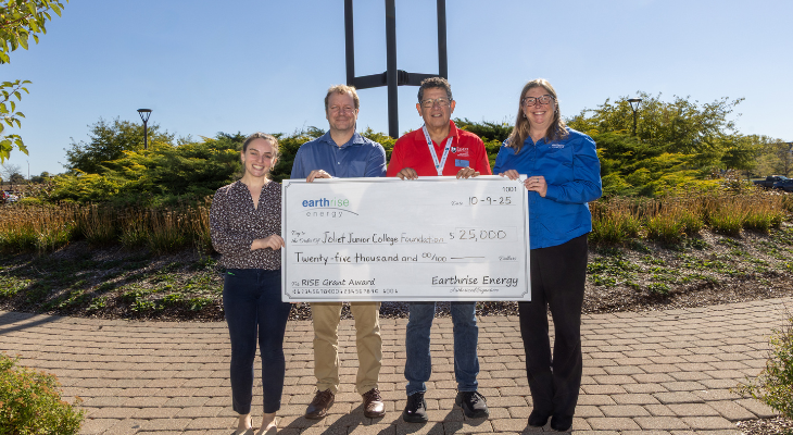 Four JJC employees stand in front of bell tower holding a big check.