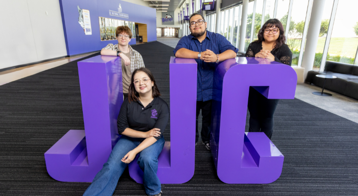 four students pose with large purple jjc letters 