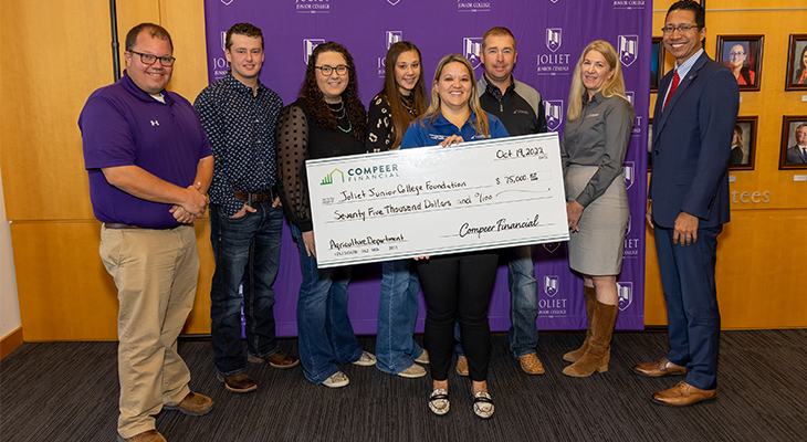 eight people pose for photo with big check in front of purple JJC backdrop