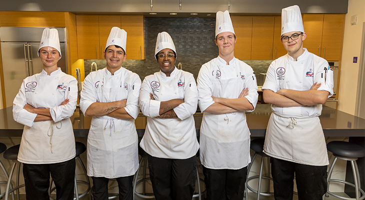 five culinary students pose for photo in chef outfit