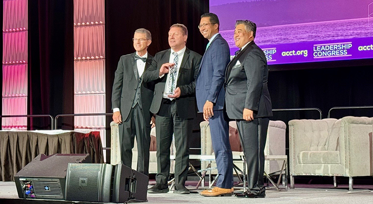 four people pose on stage with award