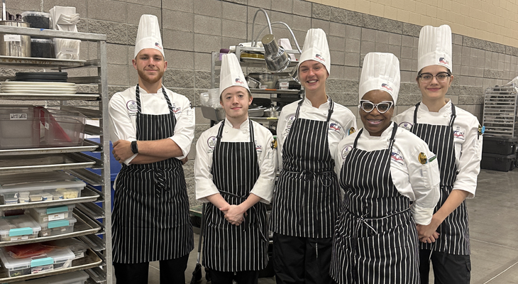 five people in chef attire pose for photo