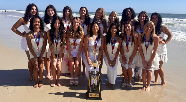 JJC cheer team poses for photo with trophy on beach