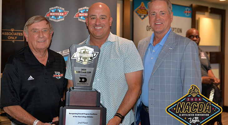 three people pose for photo with person in middle holding trophy