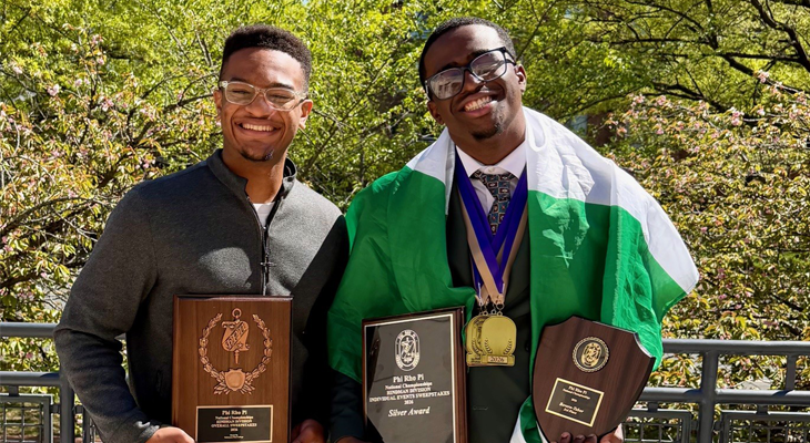 two people pose for photo with plaques and medals