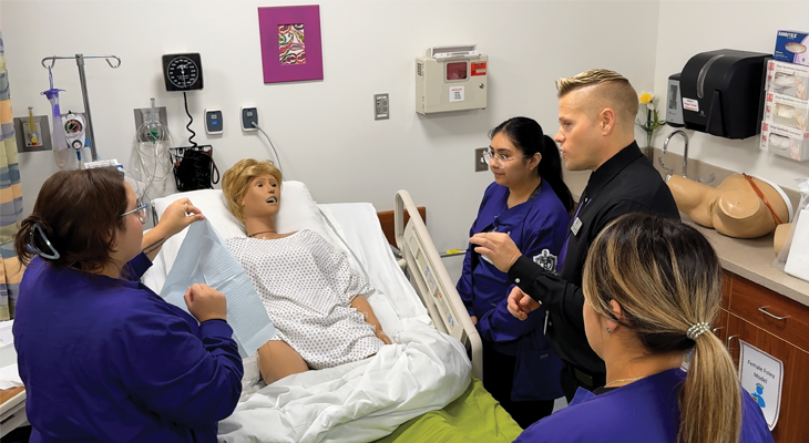 three nursing students and professor in nursing lab classroom