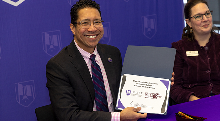 Dr. Clyne Namuo poses for photo while holding signed certificate