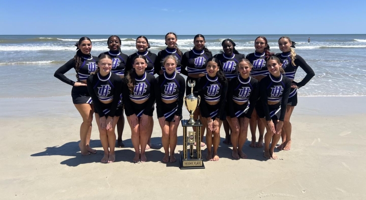 cheerleading team on beach posing for photo with trophy