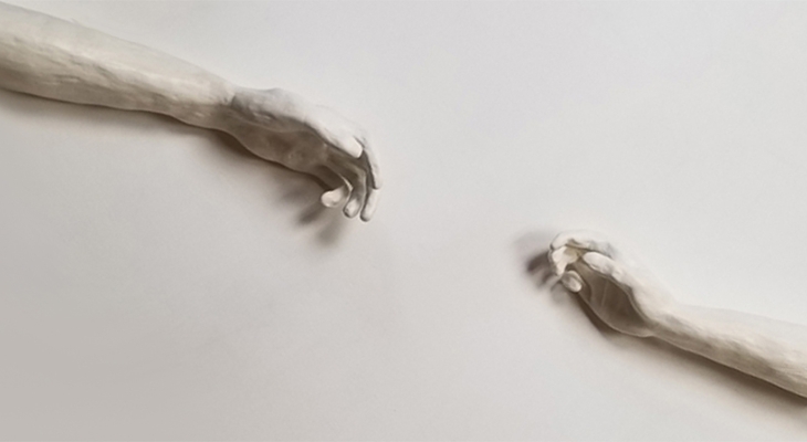 photo of sculpture of two hands reaching for the other