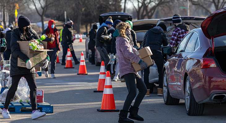 people bring boxes of food to cars in drive-up food drive